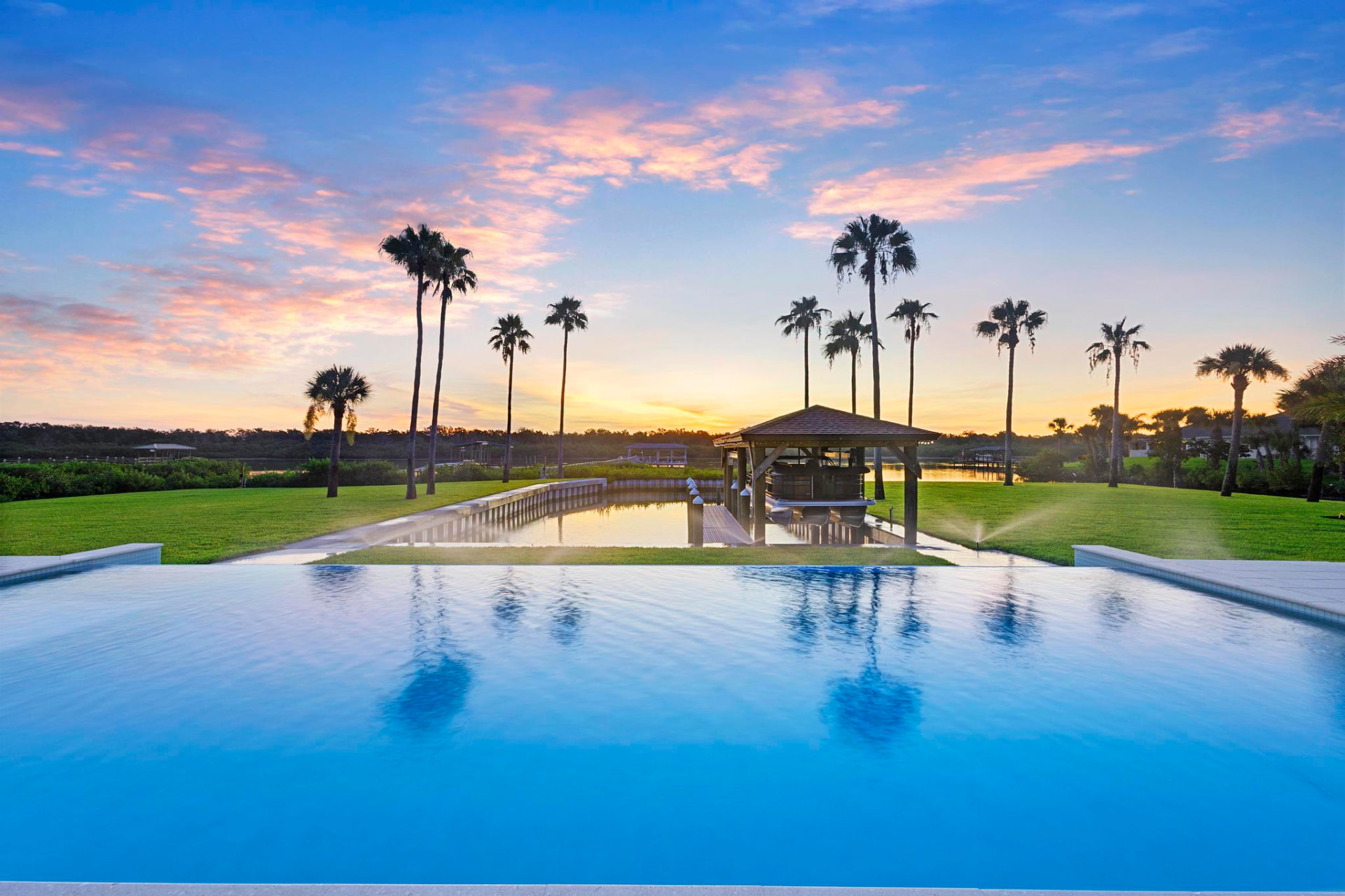 Custom infinity pool overlooking a New Smyrna Beach waterway at sunset