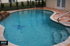 Free form pool with pink travertine decking and real rock waterfall
